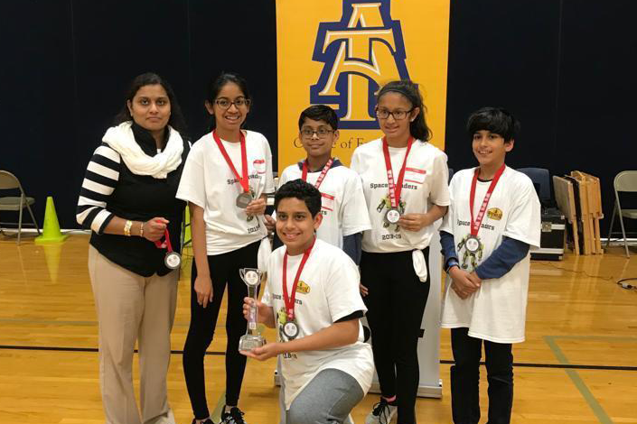 FIRST LEGO League team, the Space Invaders, show their medals
