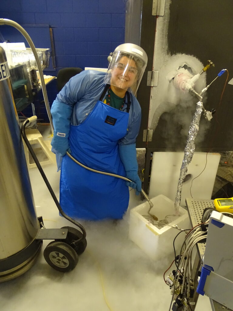 Adams fills a container with liquid nitrogen, which covers her feet and legs with vapor. 