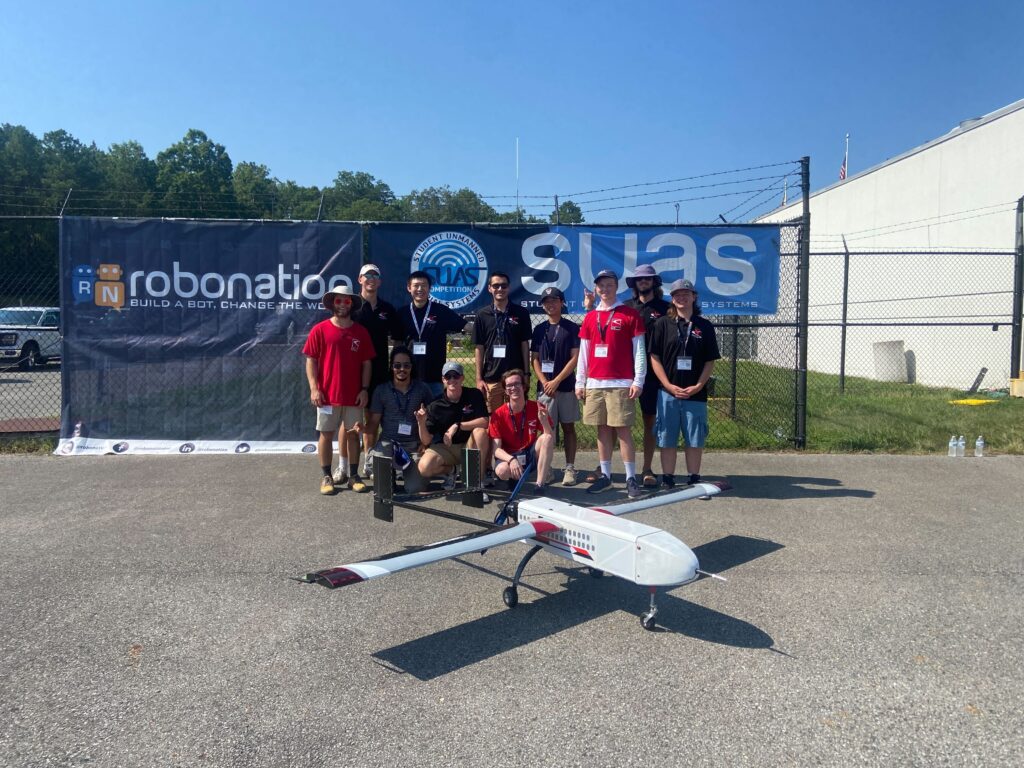 A group of eight people standing on asphalt behind a small aircraft