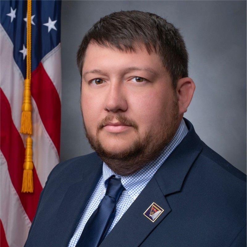 Randall Lewis headshot in front of an American flag