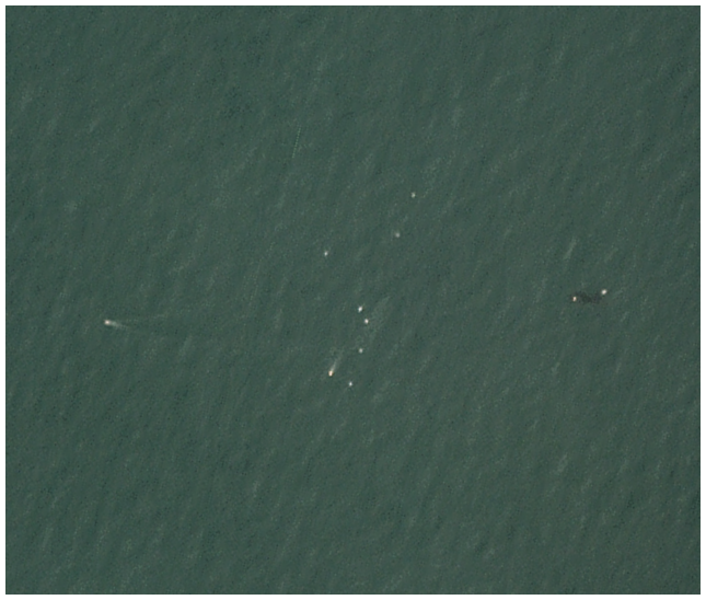 A closer view reveals tiny white dots showing the location of small boats near the artificial reef.