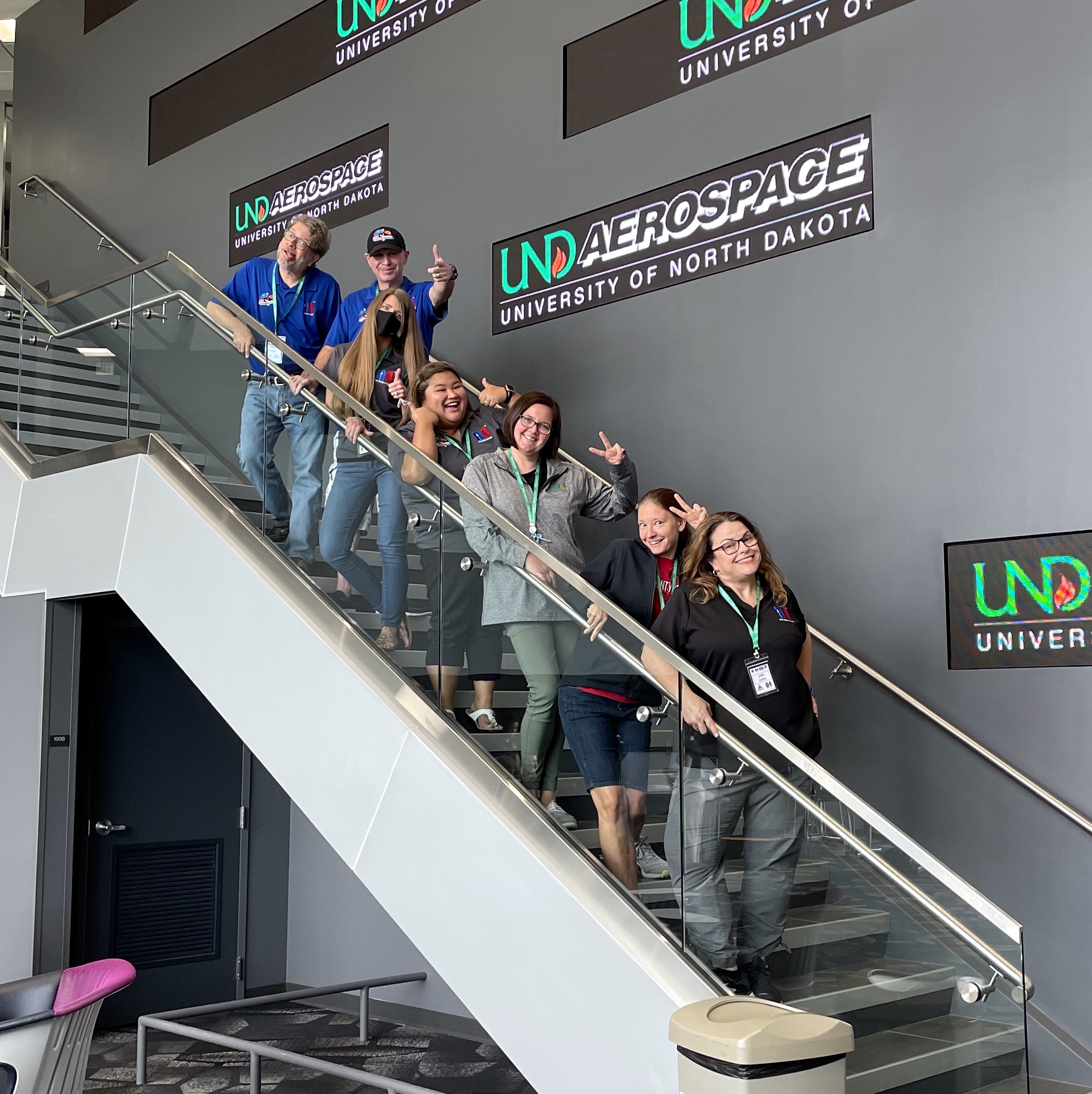 A group of people posing on a staircase. The sign behind them reads: UND aerospace, University of North Dakota